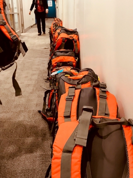 Photo: Assembled backpacks lined up, waiting to be packed into boxes